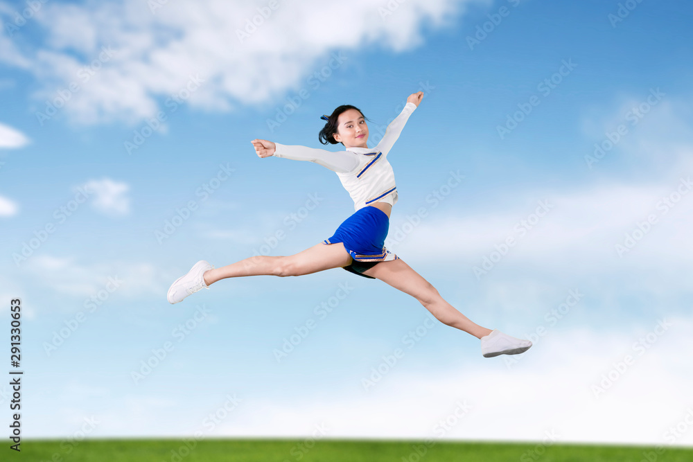 Cheerleader girl jumps and doing splits in the field Cheerleader girl jumps and doing splits in the field