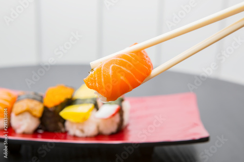 Chopsticks holding tasty sushi of salmon
