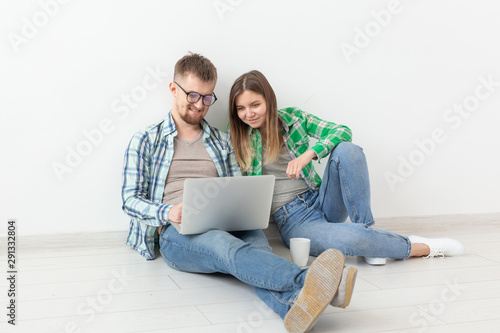 Charming young woman and a smiling man are watching online stores using a laptop to buy plumbing in a new apartment. Housewarming and repair concept.