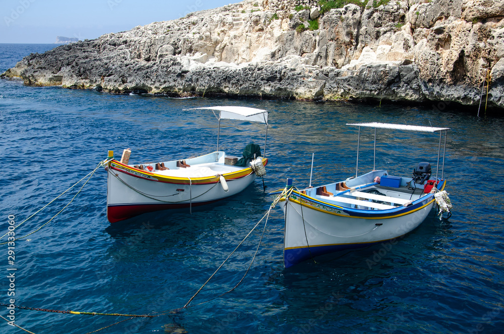 Small tourist boats moored in the Wied iz-Zurrieq harbor near the Blue Grotto sea caves in Malta.