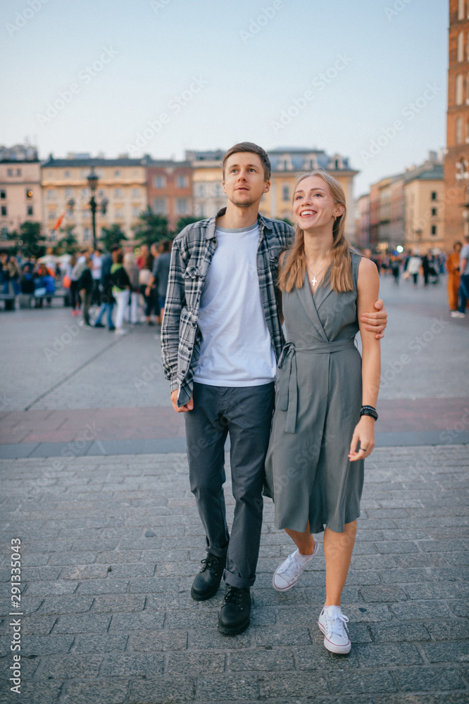 Happy loving couple smiling and walking throug the main square in Krakow (Cracow)