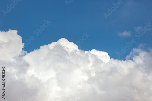 Big fluffy white clouds against a bright clear blue sky background