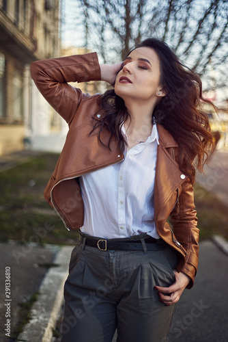 Classic beauty portrait of young woman with blue eyes and dark hair, weared in white shirt and jacket. Street shot