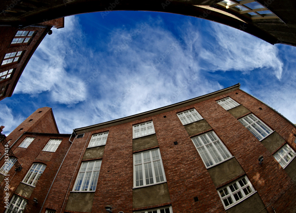 Fototapeta premium A fish eye image of an old factory building with blue sky above