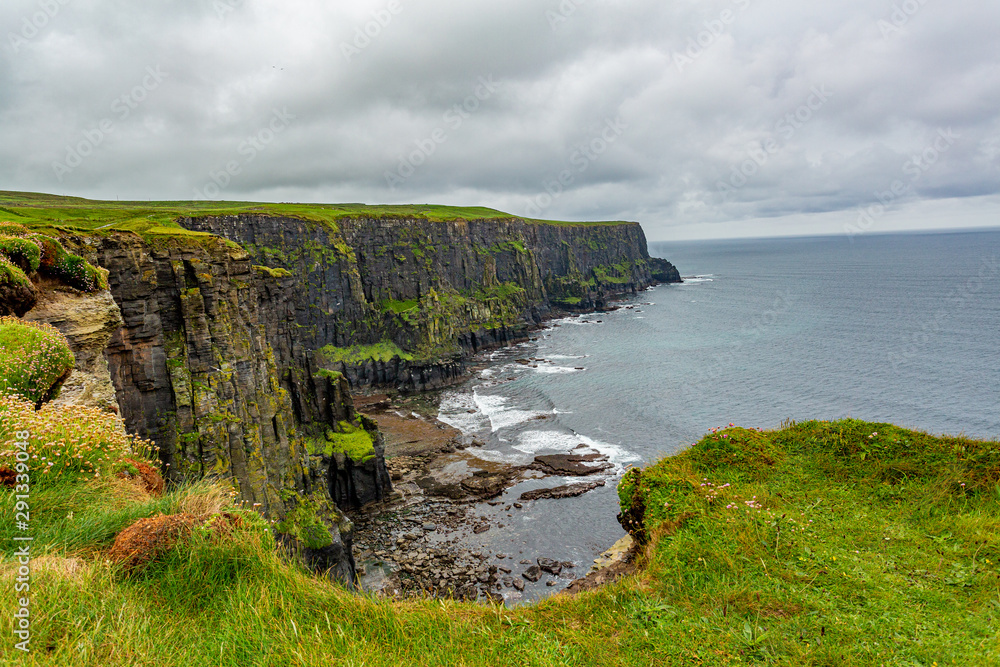 Irish countryside and rocky cliffs along the coastal walk route from Doolin to the Cliffs of Moher, geosites and geopark, Wild Atlantic Way, rainy day in county Clare in Ireland