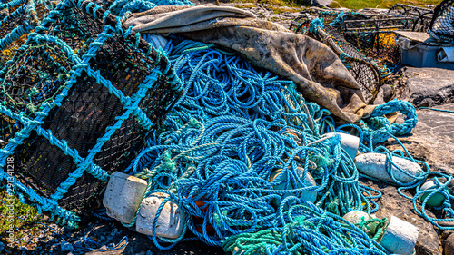 Accumulation of marine litter, such as fishing nets, ropes, lobster / crab cages or fishing traps on the rocky coastal beach of the island of Inis Oirr, sunny day on the island of Inisheer in Ireland photo