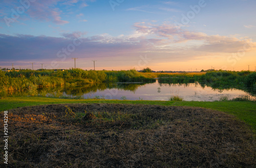 Rural landscape at sunset, clouds, fields, countryside, flares, grain and pond in front, lake, nature, reeds