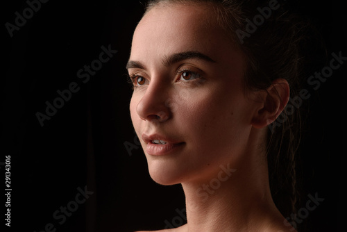 portrait of a young beautiful brunette girl on a black background