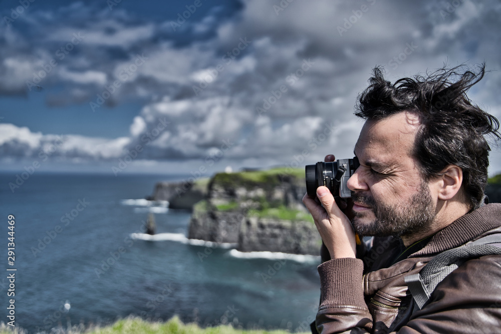 Obraz premium Side view of a professional photographer taking pictures of seascape