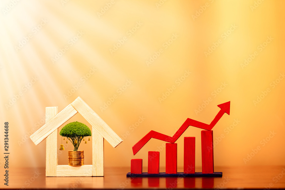 Money bags of tree on gold coin in the wooden home model and red arrow and bar graph with growing value on sunlight on brown background, Loan and business investment for real estate concept. Money bags of tree on gold coin in the wooden home model and red arrow and bar graph with growing value on sunlight on brown background, Loan and business investment for real estate concept.