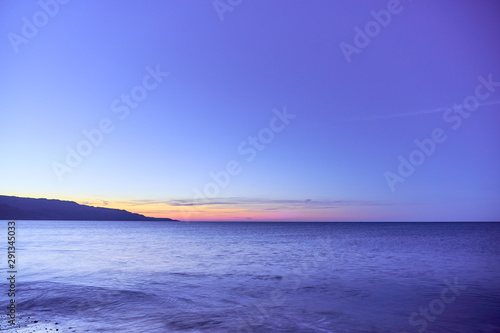  Waving sea water on a sunset against a blue sky. Copy space.