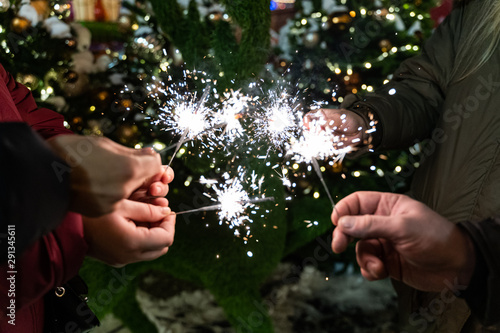 Group of friends burning Bengal lights during winter time celebrations, Christmas, New Year's Eve.