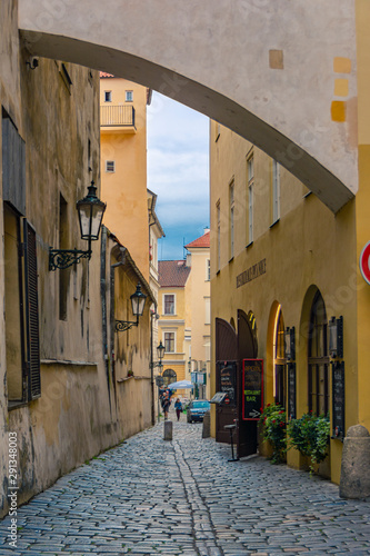 A narrow, deserted, cozy street in an old European city with open doors to shops