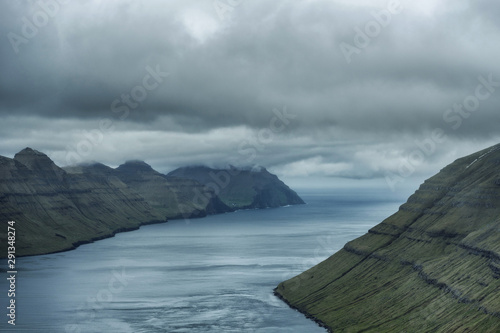 Spectacular views of the scenic fjords on the Faroe Islands with cloud-covered mountains.