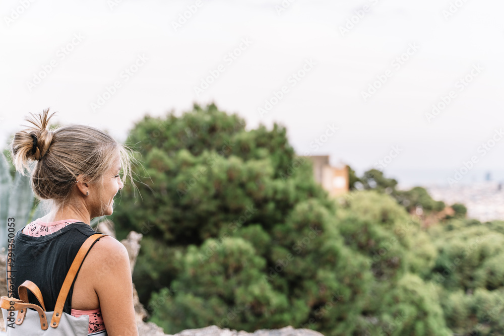 smiling blond woman standing in a lookout point.