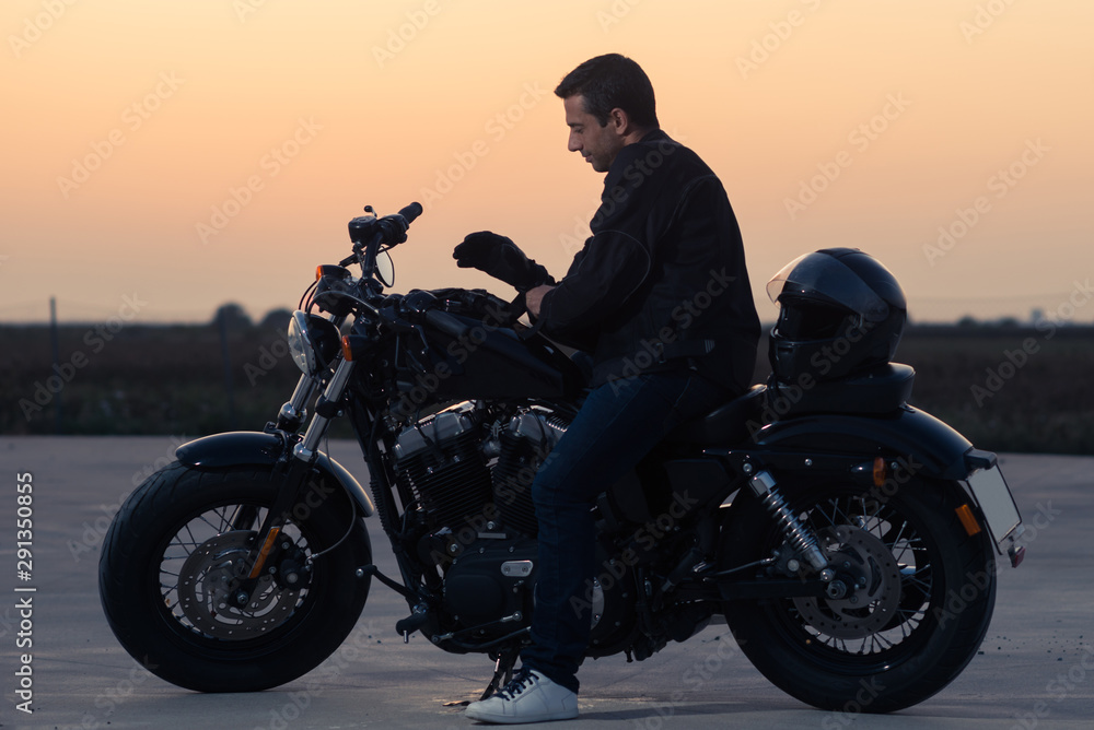 Black dressed biker man putting on a pair of gloves. Black dressed biker man putting on a pair of gloves.
