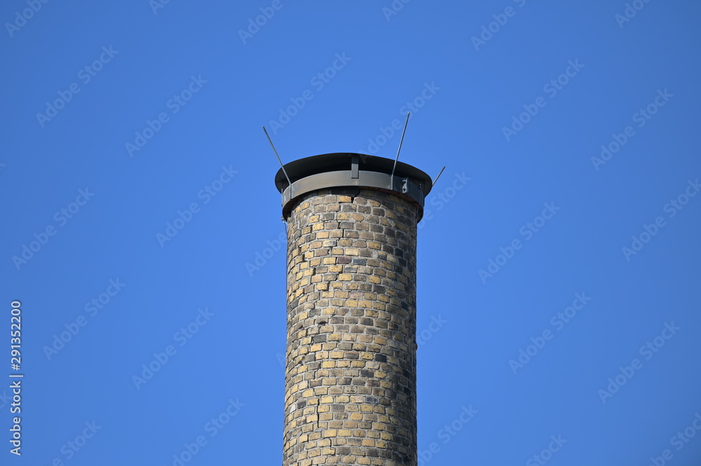 An old an industrial chimney in front of a blue sky.