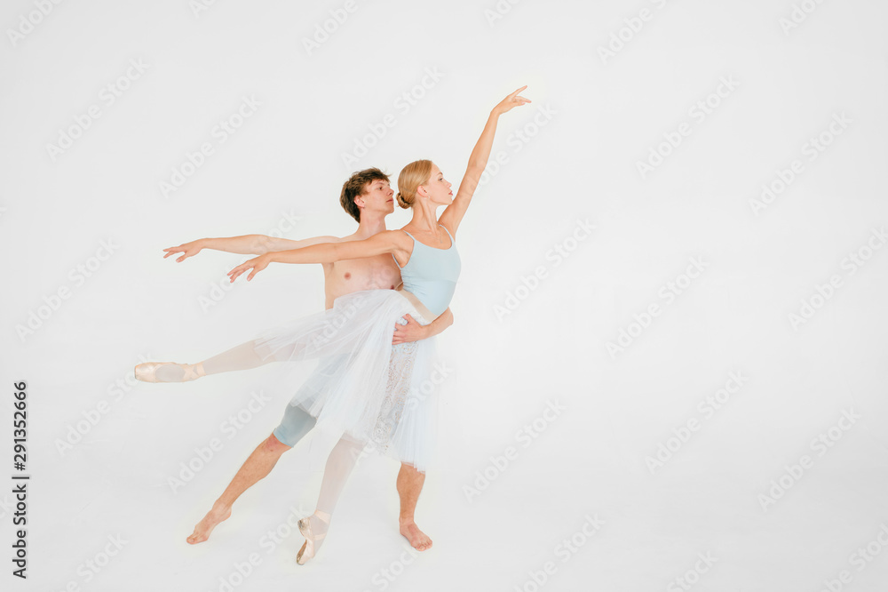 Young couple of modern ballet dancers posing over white studio background
