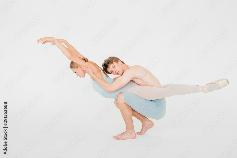 Fototapeta premium Young couple of modern ballet dancers posing over white studio background
