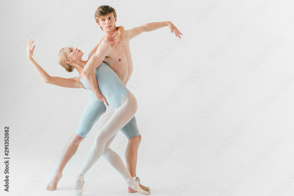 Young couple of modern ballet dancers posing over white studio background Young couple of modern ballet dancers posing over white studio background