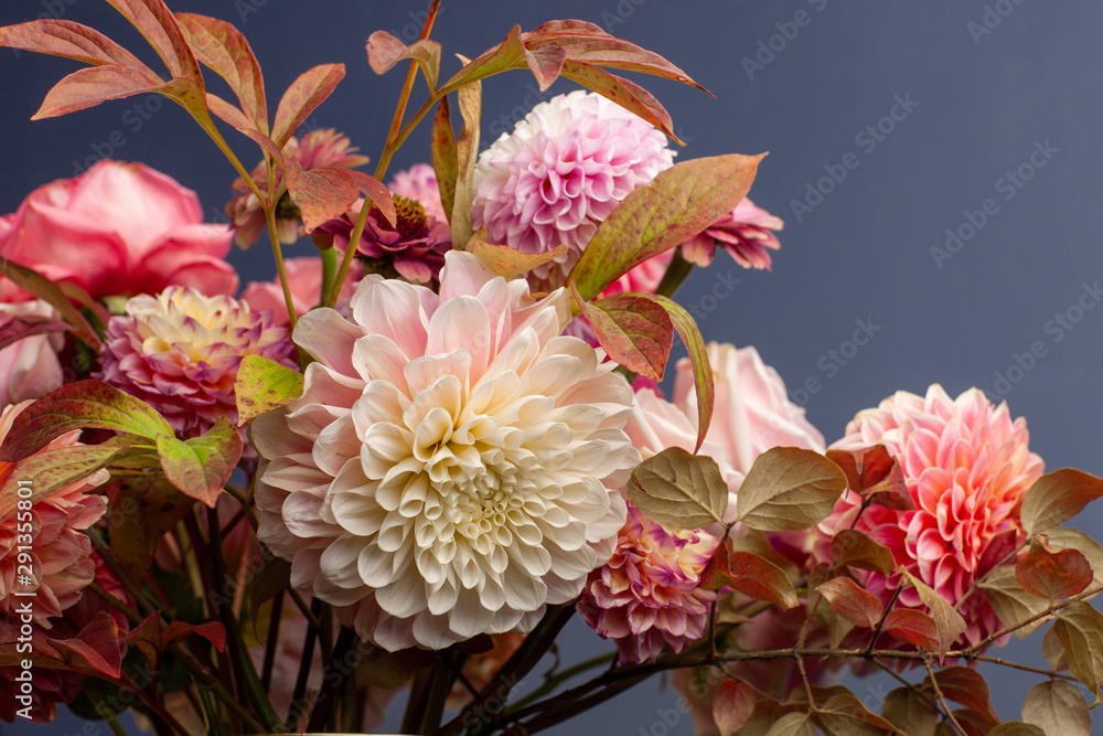 Floral composition of dahlia flowers, roses and autumn leaves. Arty, bright red and pink color bouquet of flowers on a blue background Floral composition of dahlia flowers, roses and autumn leaves. Arty, bright red and pink color bouquet of flowers on a blue background