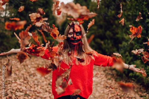 Young blonde girl with halloween face art posing outdoor. Helloween celebration concept.