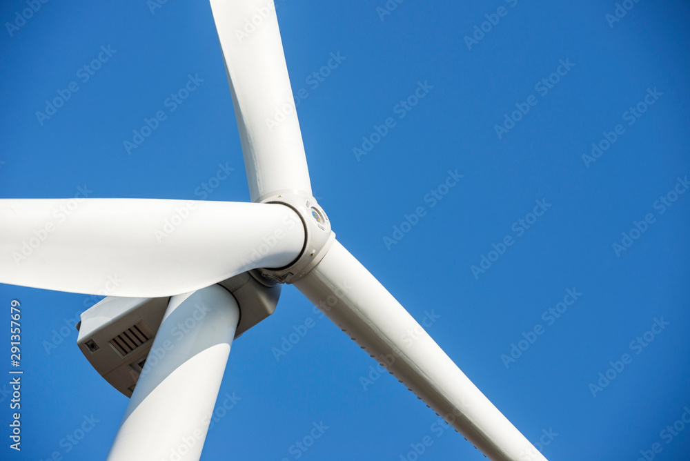 Wind turbines generating electricity with blue sky. Close up of Wind turbine producing alternative energy Wind turbines generating electricity with blue sky. Close up of Wind turbine producing alternative energy