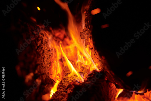 Close up of bonfire with a sparks at night. Heat from burning logs and coals in the dark