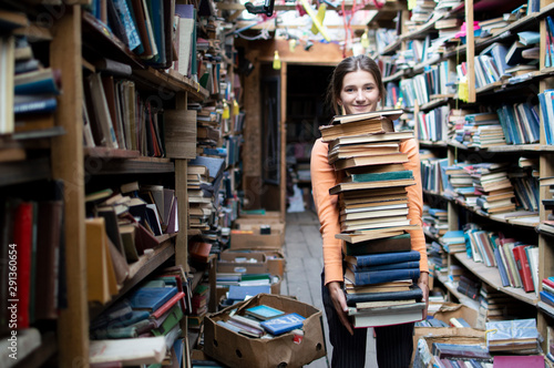 girl student carries a large stack of books in the library, preparation for study, knowledge is power, concept