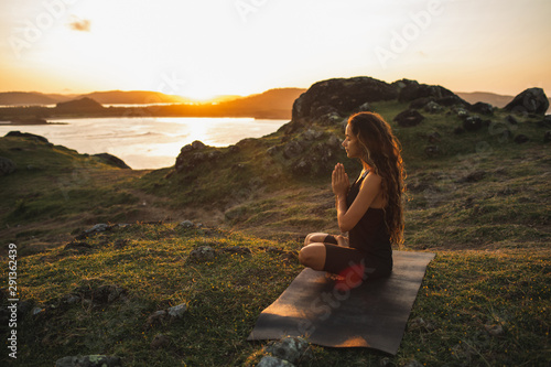 Canvas Print Woman doing yoga alone at sunrise with mountain and ocean view