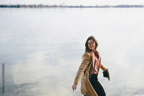 Lady in coat on the river bank Portrait of beautiful fashion woman.