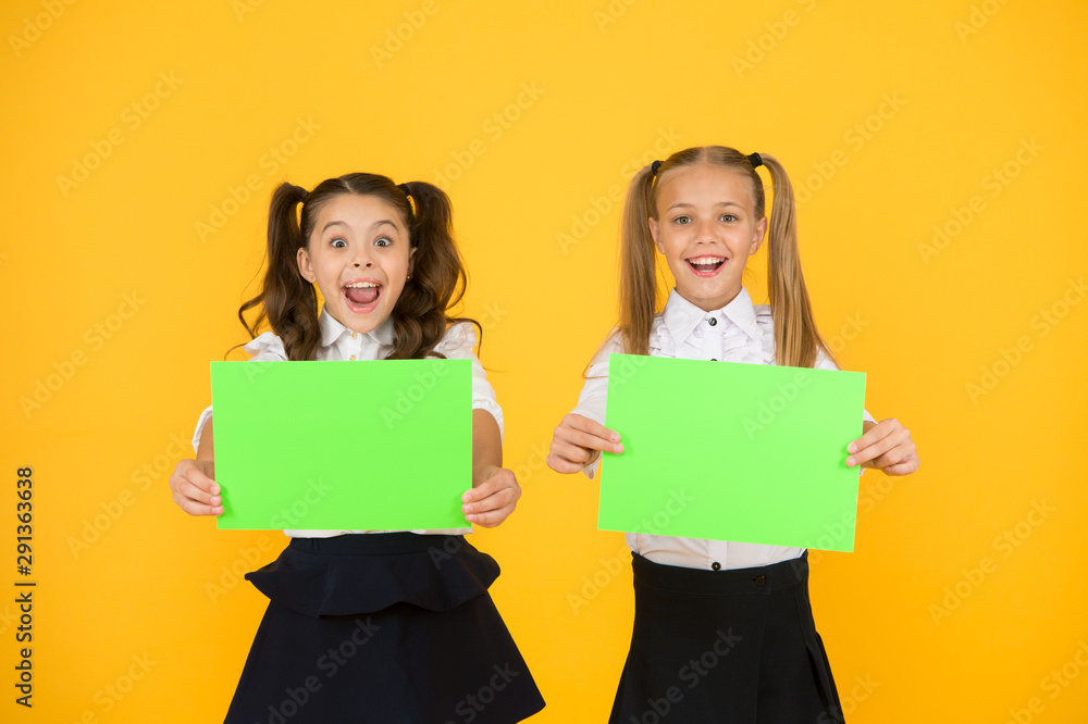 Genius advertising and marketing. Happy genius children holding blank paper sheets on yellow background. Genius girls smiling with empty posters. Genius idea, copy space Genius advertising and marketing. Happy genius children holding blank paper sheets on yellow background. Genius girls smiling with empty posters. Genius idea, copy space