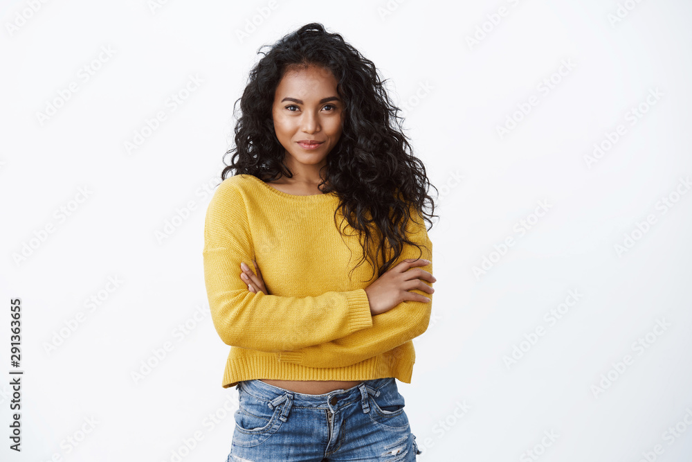 Alluring young african american female with dark curly hairstyle, smiling determined and motivated, cross arms chest confident pose, smiling daring camera, white background Alluring young african american female with dark curly hairstyle, smiling determined and motivated, cross arms chest confident pose, smiling daring camera, white background