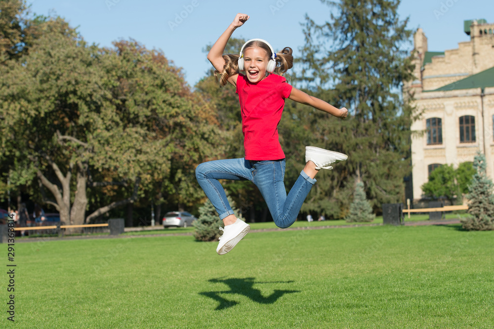 Free and joyful. Girl listening music modern gadget. Kid happy with wireless headset dancing running jumping. Stereo headphones. Kid using modern technology. Modern child. Perfect loud sound