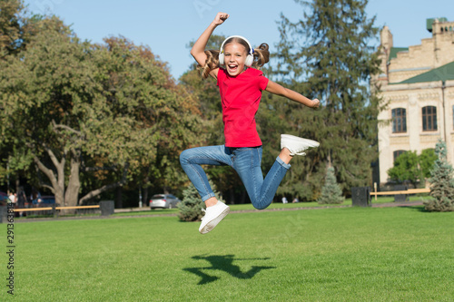 Free and joyful. Girl listening music modern gadget. Kid happy with wireless headset dancing running jumping. Stereo headphones. Kid using modern technology. Modern child. Perfect loud sound