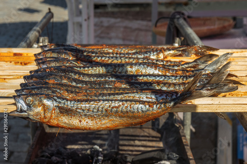 Fresh grilled mackerel fish on the wooden stick. Fish kebab. Naplavka street food market. photo