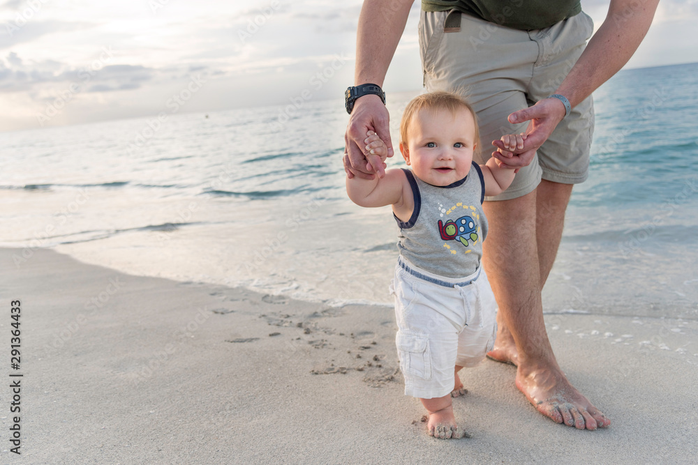 father and son on the beach, baby walking