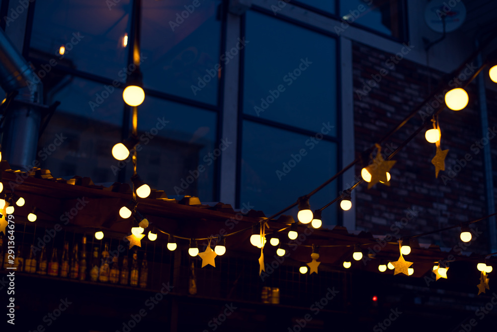 Garland with lights and stars in a street bar in the evening.