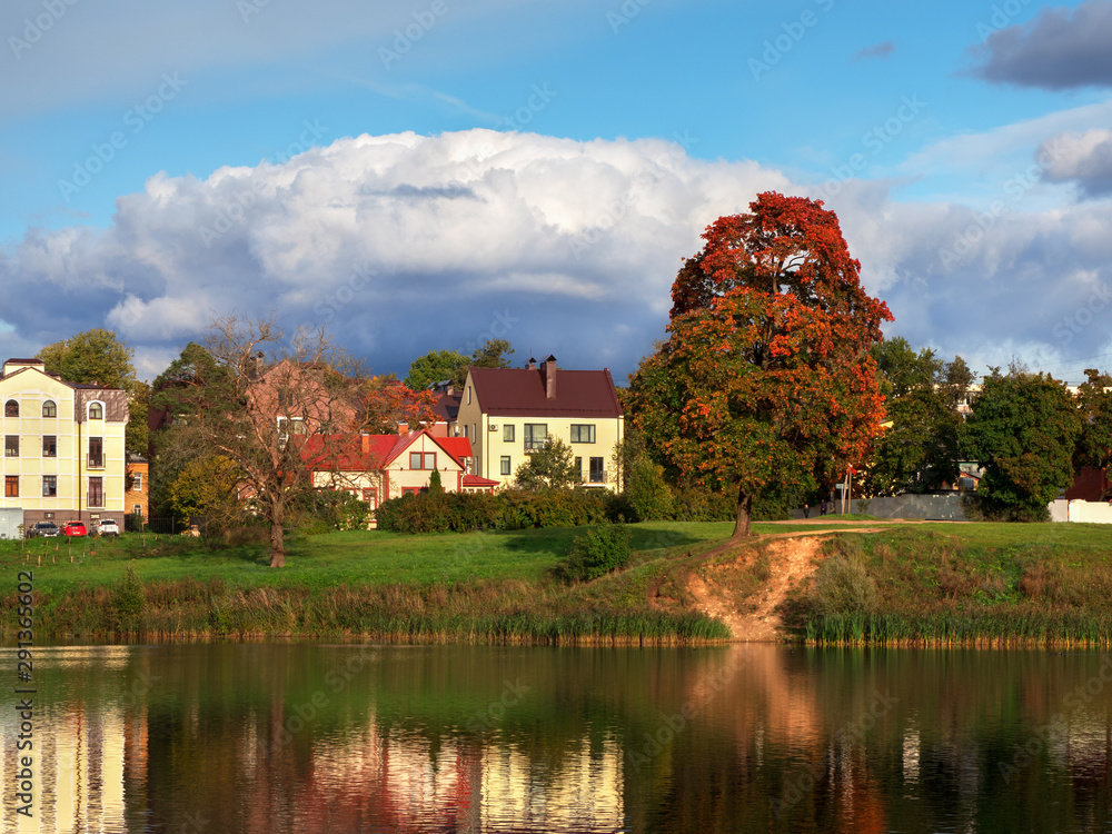 Bright colorful autumn landscape with houses by the water.