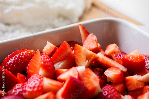 Close up of cut red strawberries in a white bowl. Landscape format.