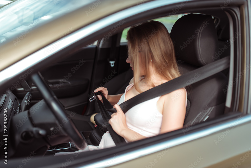 Girl woman in car summer city, fastens seat belt while sitting on seat, beginning of movement, concept of security, save lives, the activation of airbags.