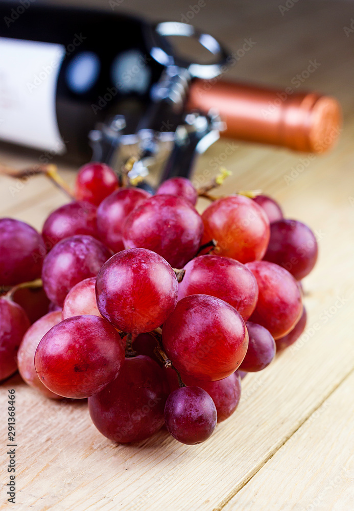 FIRST PLANE OF GRAPES WITH WINE BOTTLE AND CORKSCREW ON WOODEN TABLE. VINTAGE TIME FIRST PLANE OF GRAPES WITH WINE BOTTLE AND CORKSCREW ON WOODEN TABLE. VINTAGE TIME
