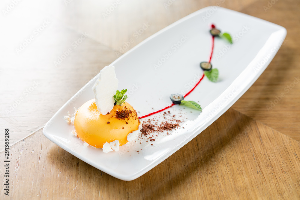 Yellow mousse-cake. French dessert, blueberry, mint and a piece of meringue on a white plate. Stylishly decorated. Restaurant menu Yellow mousse-cake. French dessert, blueberry, mint and a piece of meringue on a white plate. Stylishly decorated. Restaurant menu