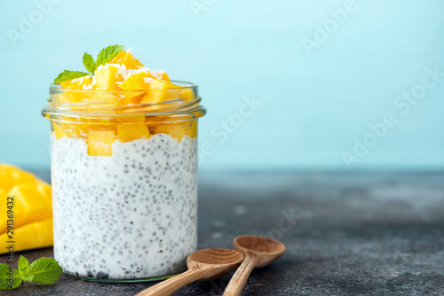 Chia pudding with mango in jar. Healthy food, vegan vegetarian diet concept. Blue background, copy space for text photo