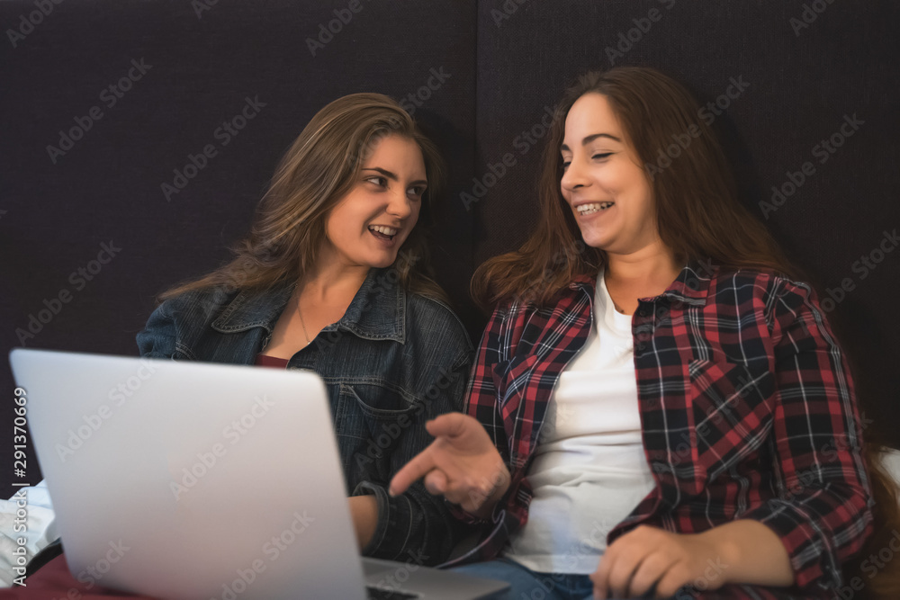Two young girls or women laughing and discussing something using laptop, female lesbian couple spend time together Two young girls or women laughing and discussing something using laptop, female lesbian couple spend time together