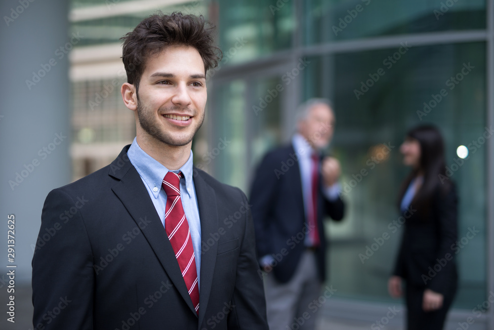 Smiling young businessman walking in a business environment Smiling young businessman walking in a business environment