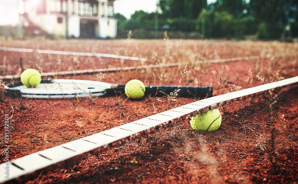 Ruined tennis court with a racket and balls. Sport, recreation concept