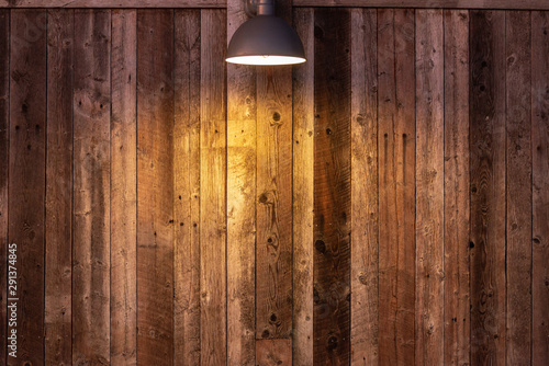 Glowing light bulb on wooden background. Light falling from old vintage lamp on wall.