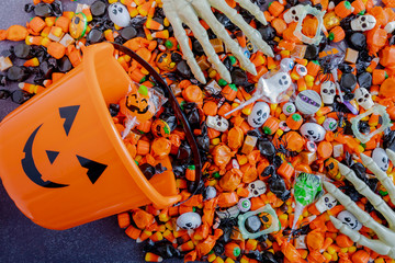 Halloween candy spilling out of orange pumpkin bucket