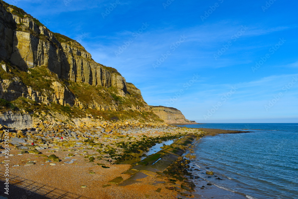 The dramatic south coast of England. Cliffs, shingle beach and crystal clear sea on a bright sunny day. Hastings, Sussex county, South East England